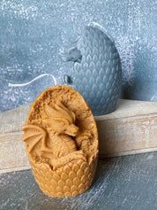 Handmade dragon egg candle with sculpted dragon, crafted from soy wax, displayed with textured background, combines mythical charm and warmth.