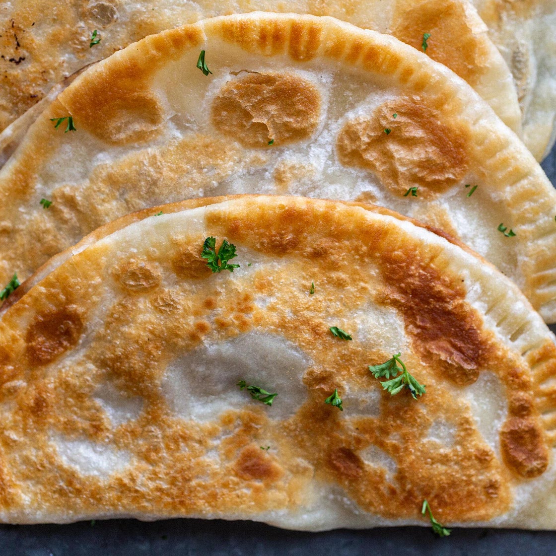 Crispy homemade Ukrainian chebureki pastries filled with flavorful beef, displaying a golden-brown, crunchy exterior.