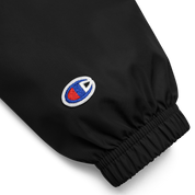 Close-up of sleeve detail on Champion packable jacket from Ukrainian Vibe Trizub Collection, showing embroidered logo on black polyester fabric.