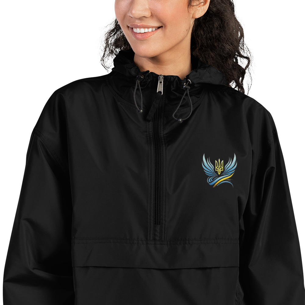 Woman wearing Ukrainian Vibe Trizub Collection embroidered Champion packable jacket, black, with hood and rain-resistant features.