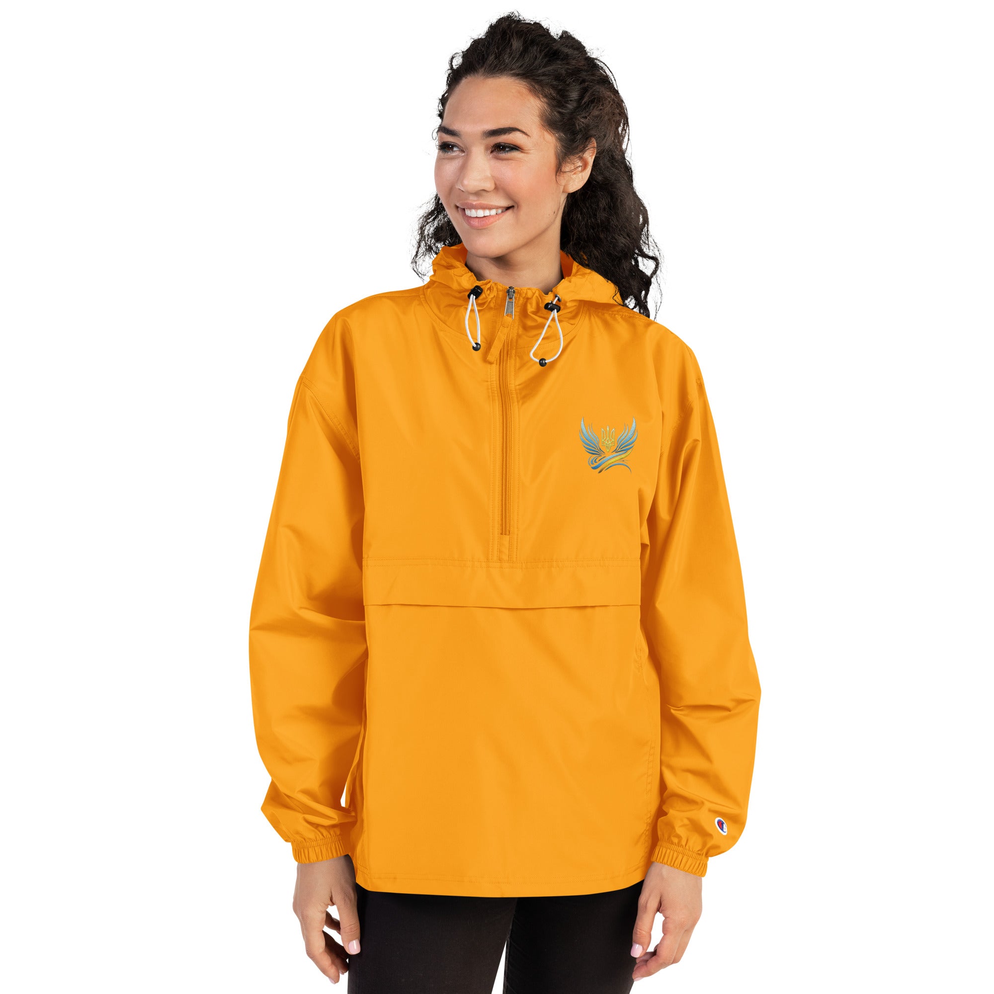 Woman wearing yellow embroidered Champion packable jacket from Ukrainian Vibe Trizub Collection with hood and kangaroo pocket.