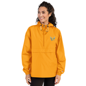 Woman wearing an orange embroidered Champion packable jacket from the Ukrainian Vibe Trizub Collection, featuring a hood and kangaroo pocket.