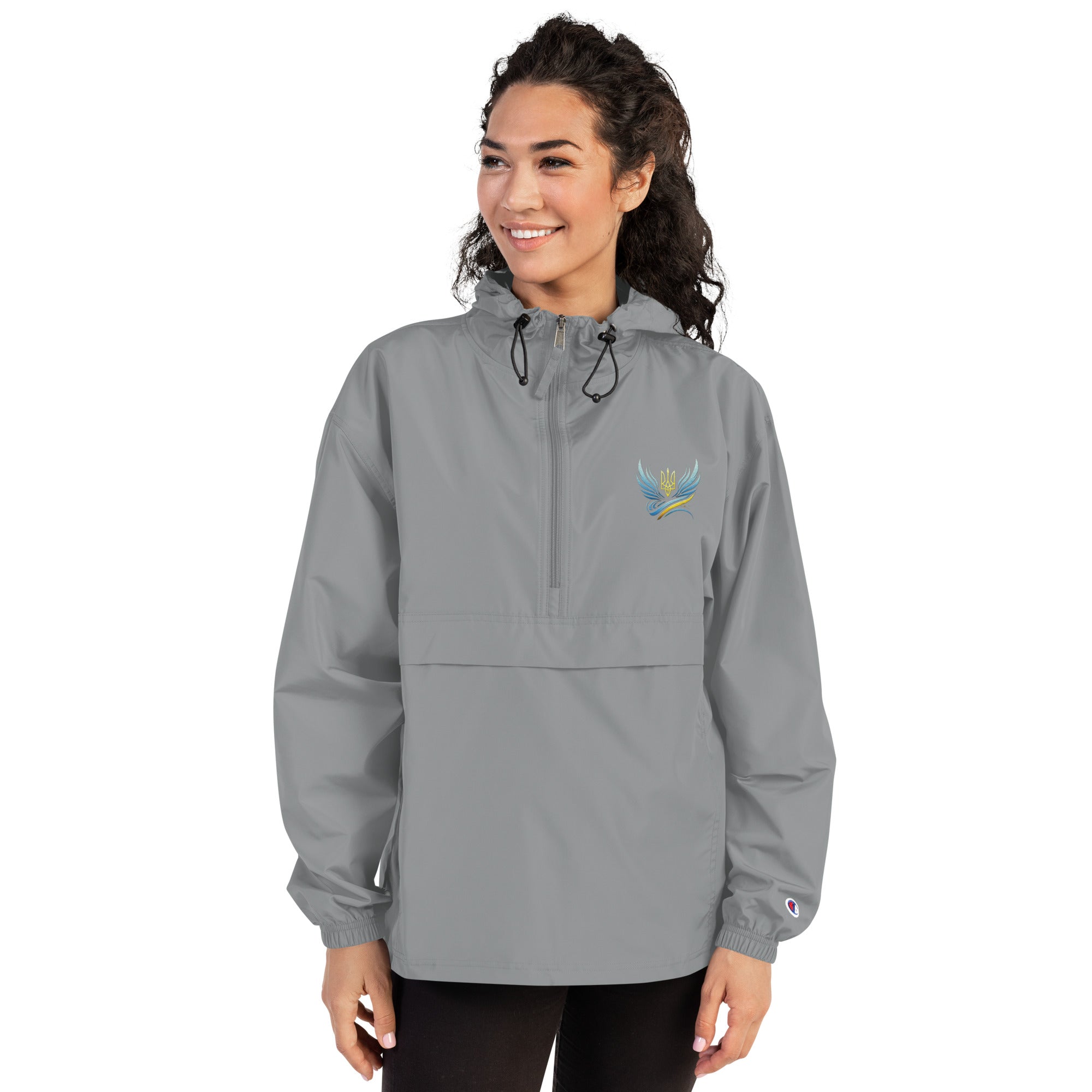 Woman wearing Ukrainian Vibe Trizub Collection embroidered Champion jacket, featuring hood and kangaroo pocket, grey color.