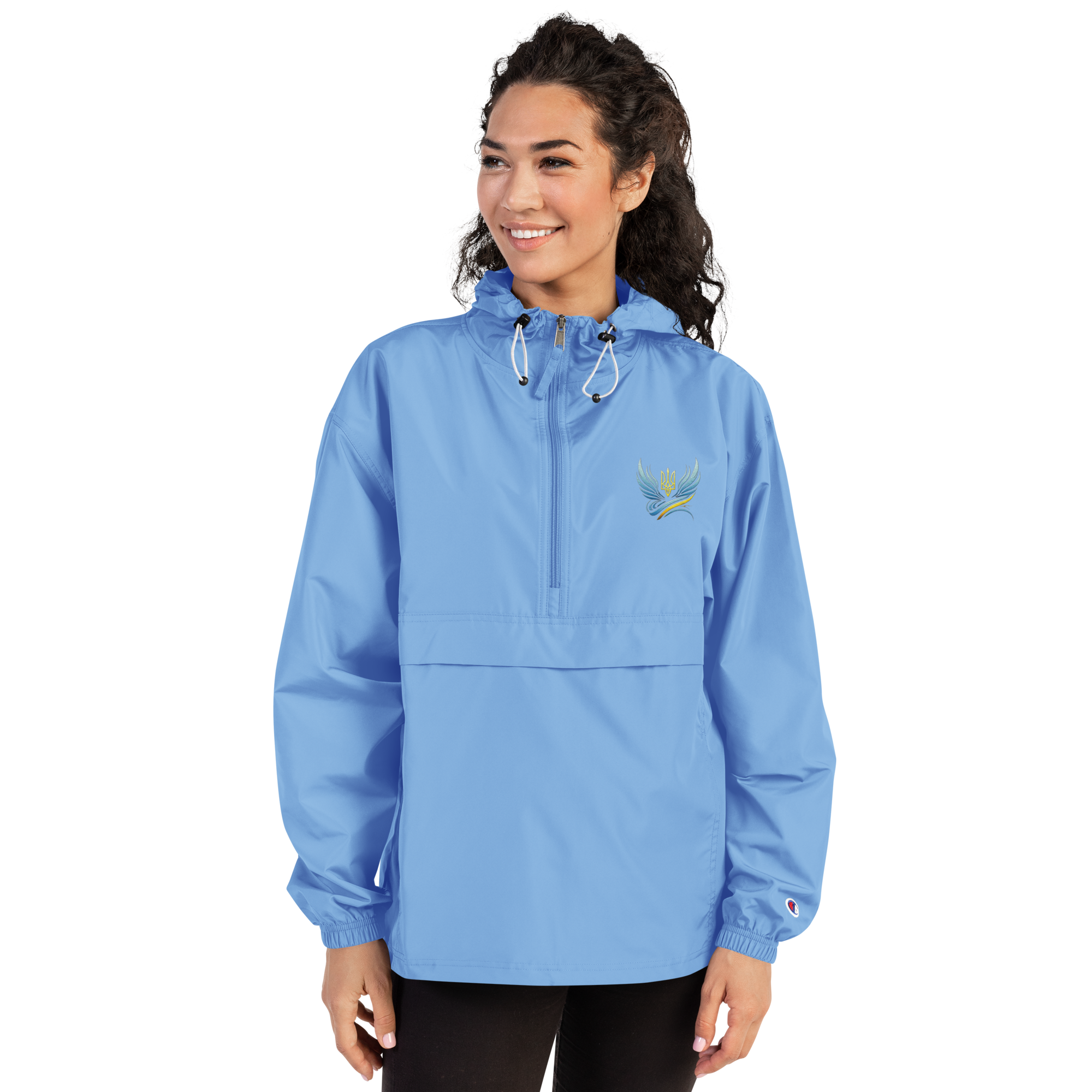 Woman wearing blue embroidered Champion packable jacket from Ukrainian Vibe Trizub Collection with hood and kangaroo pocket.