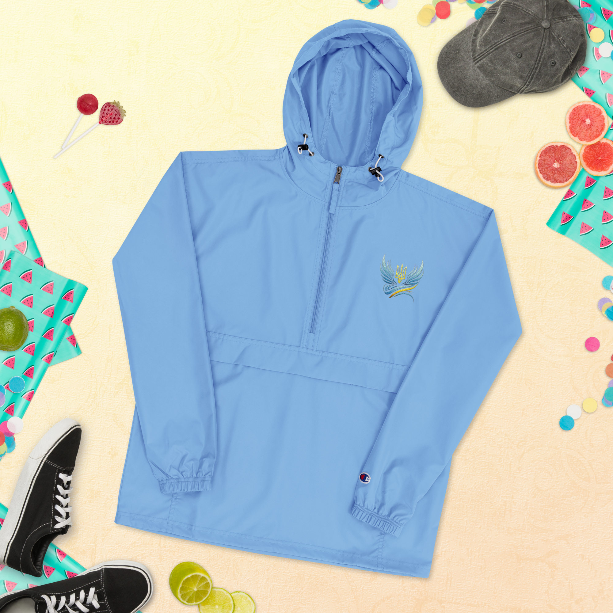 Light blue women's embroidered Champion jacket from Ukrainian Vibe Trizub Collection with hoodie, surrounded by colorful summer items.