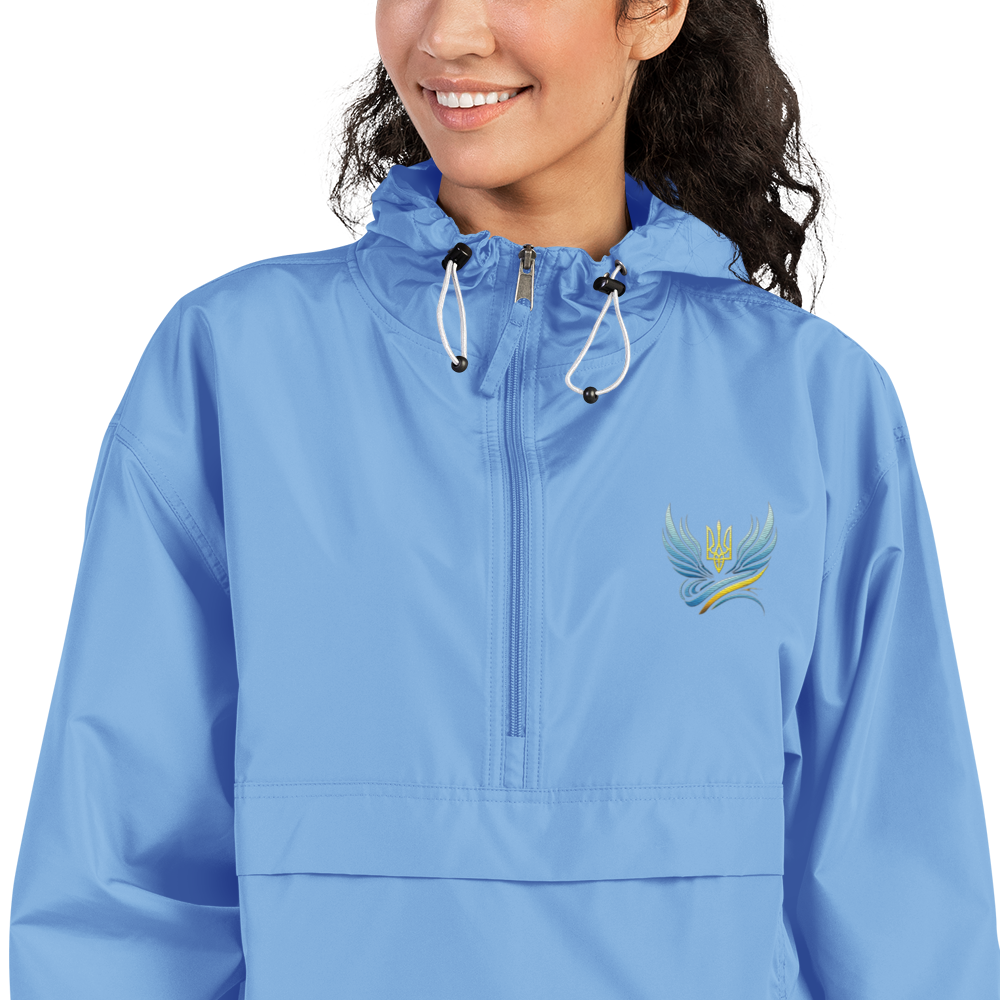 Woman wearing blue embroidered Champion packable jacket from Ukrainian Vibe Trizub Collection