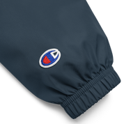 Close-up of Champion packable jacket sleeve from Ukrainian Vibe Trizub Collection, featuring embroidered logo on polyester fabric.