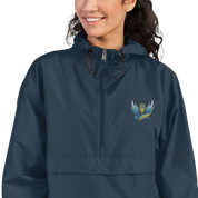 Woman wearing Ukrainian Vibe Trizub embroidered blue Champion packable jacket with hood, front pocket, and Trizub emblem.