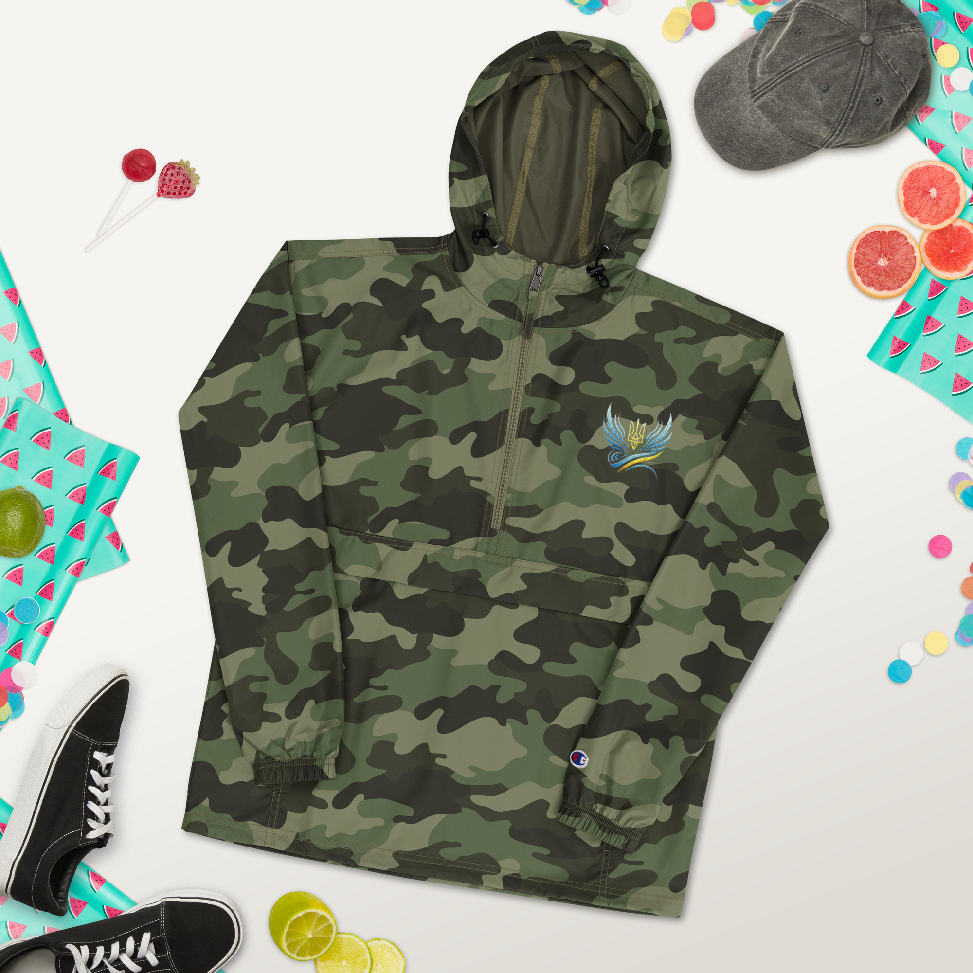 Ukrainian Vibe Trizub camo jacket for women by Champion with embroidery, rain-resistant and packable, surrounded by accessories.