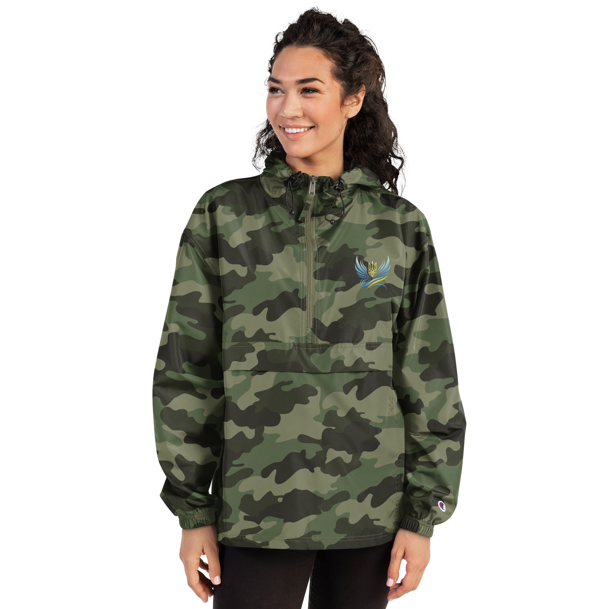 Woman in camo Ukrainian Vibe Trizub Collection embroidered Champion packable jacket, featuring a hood and kangaroo pocket.