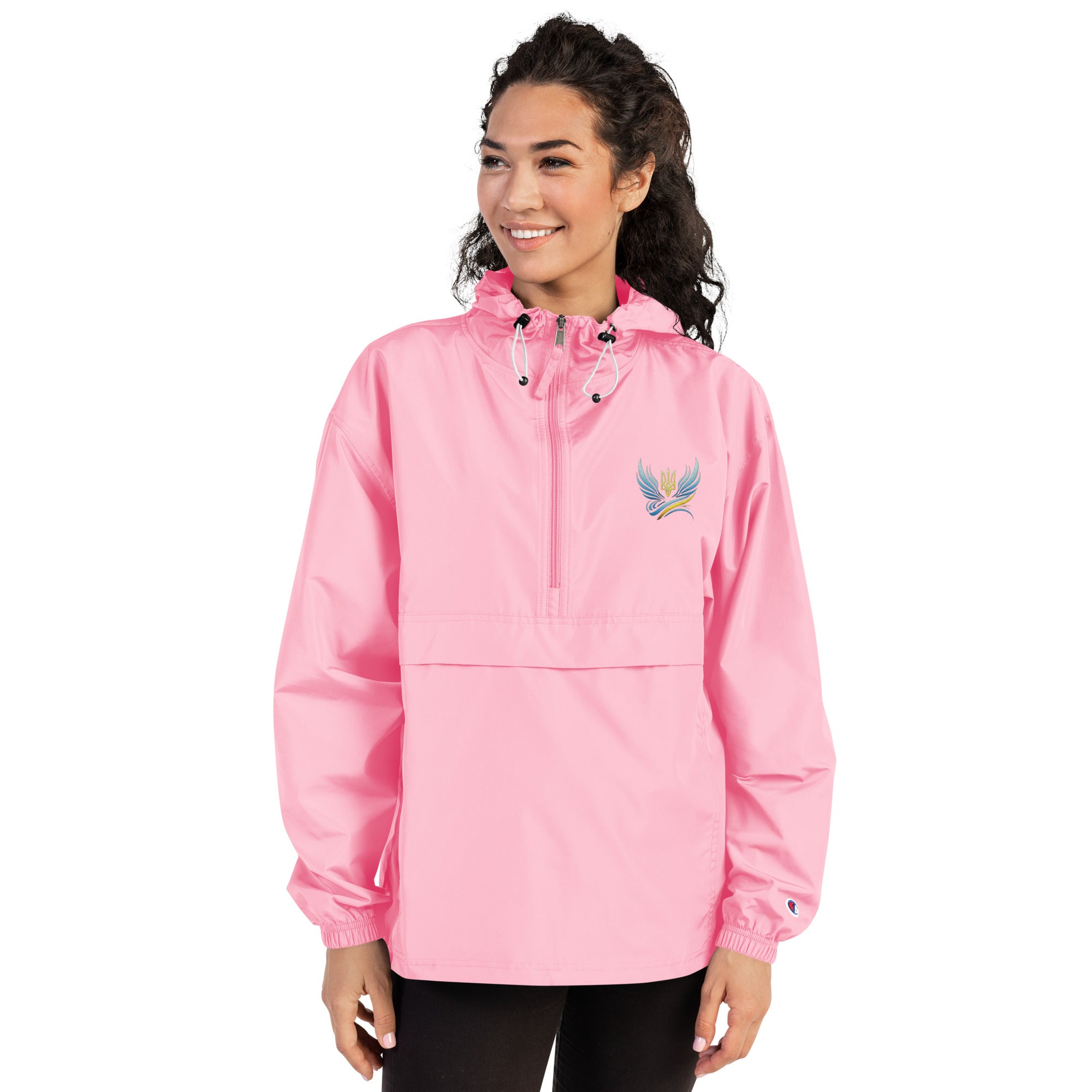 Woman wearing pink Ukrainian Vibe Trizub embroidered Champion packable jacket, featuring hood and kangaroo pocket.