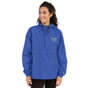 Woman wearing blue embroidered Champion packable jacket from Ukrainian Vibe Trizub Collection with hood and kangaroo pocket.
