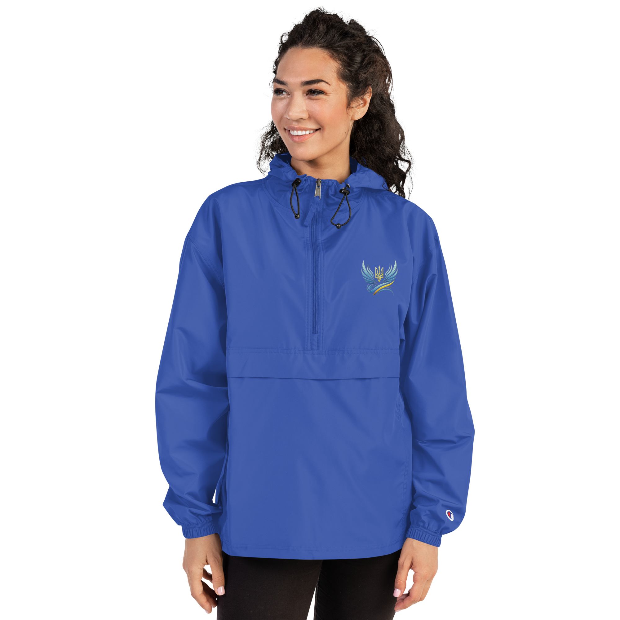 Woman wearing blue embroidered Champion packable jacket from Ukrainian Vibe Trizub Collection with hood and kangaroo pocket.