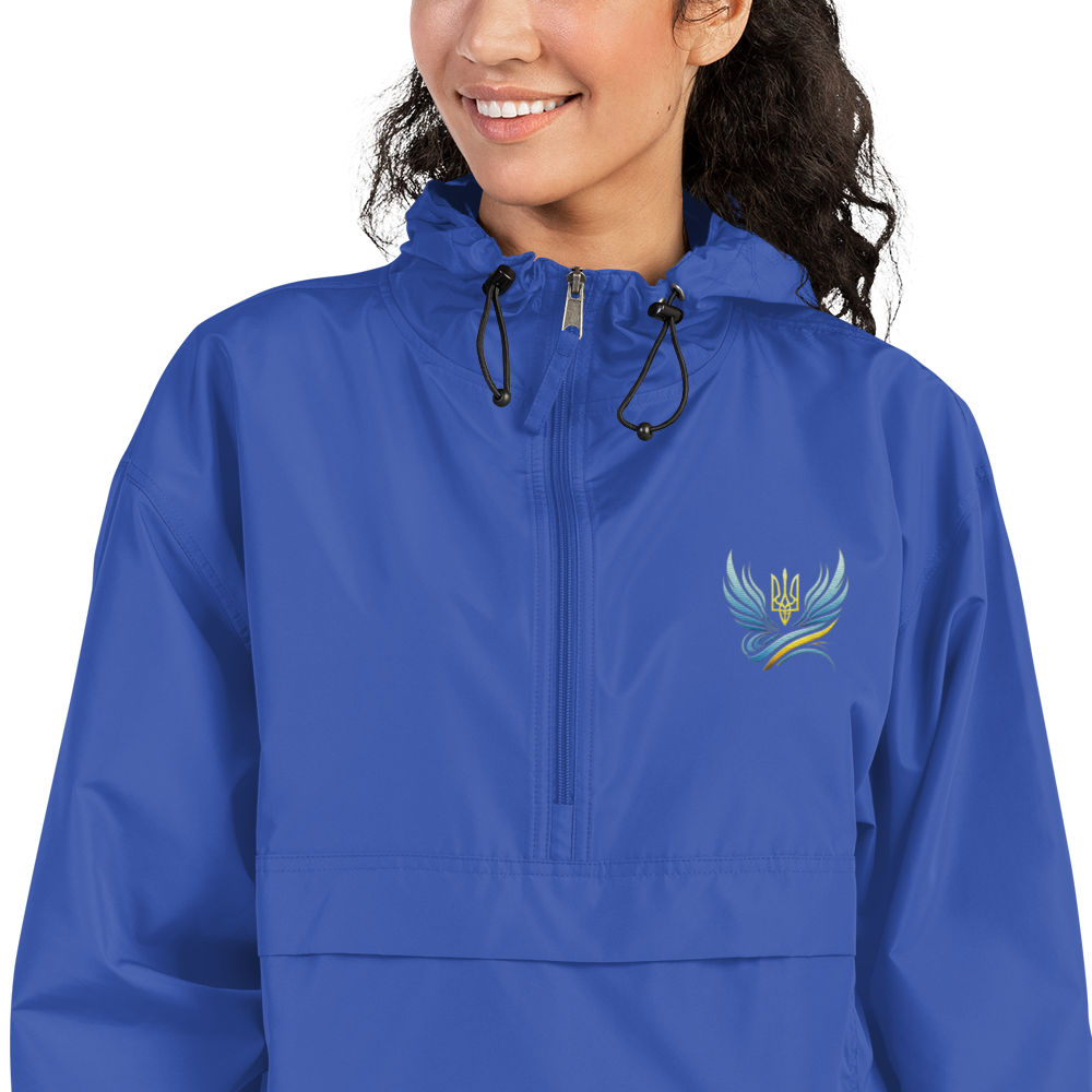 Woman wearing blue Ukrainian Vibe Trizub embroidered Champion packable jacket with hood and kangaroo pocket.