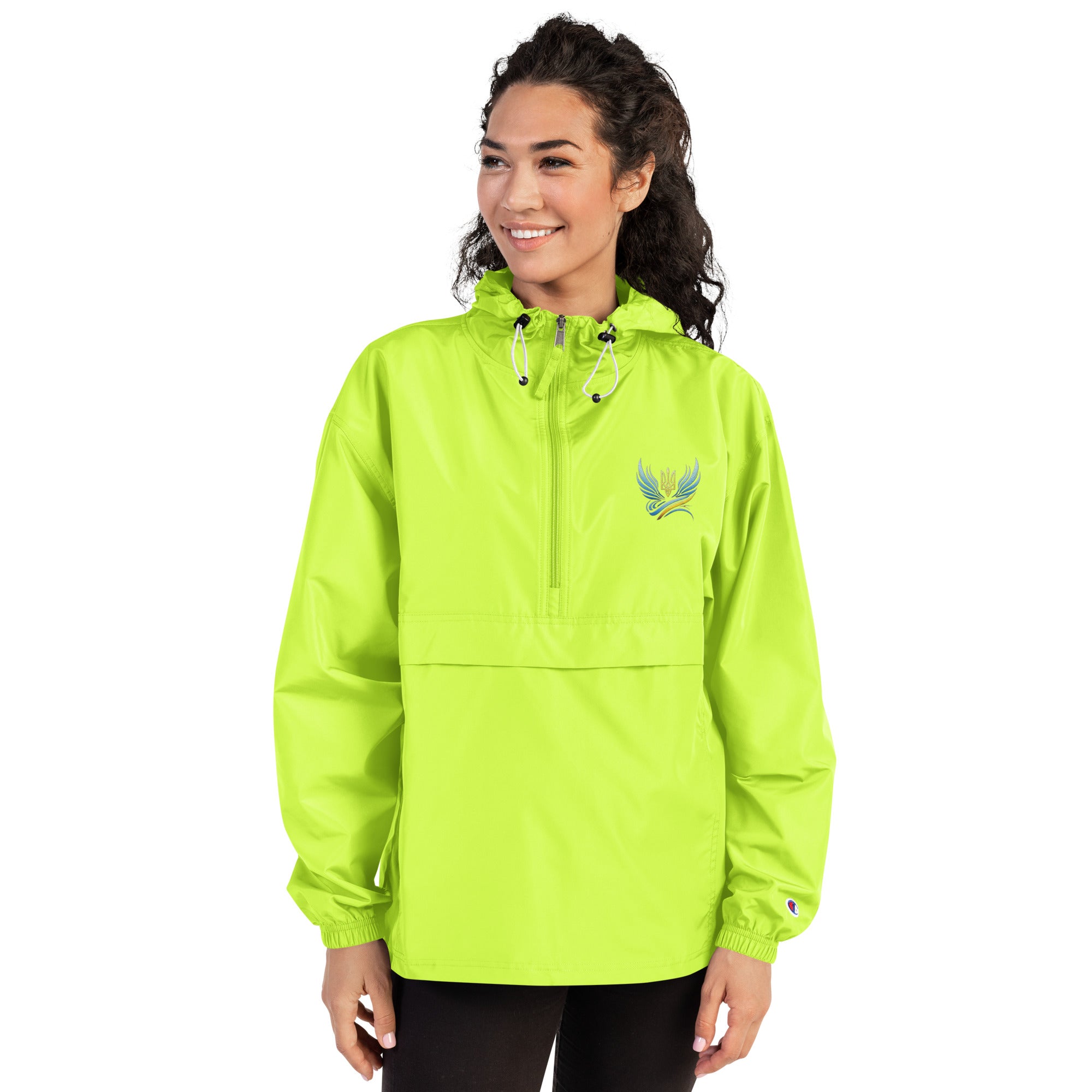 Woman wearing lime green Champion packable jacket with Ukrainian embroidery, featuring hood and kangaroo pocket.