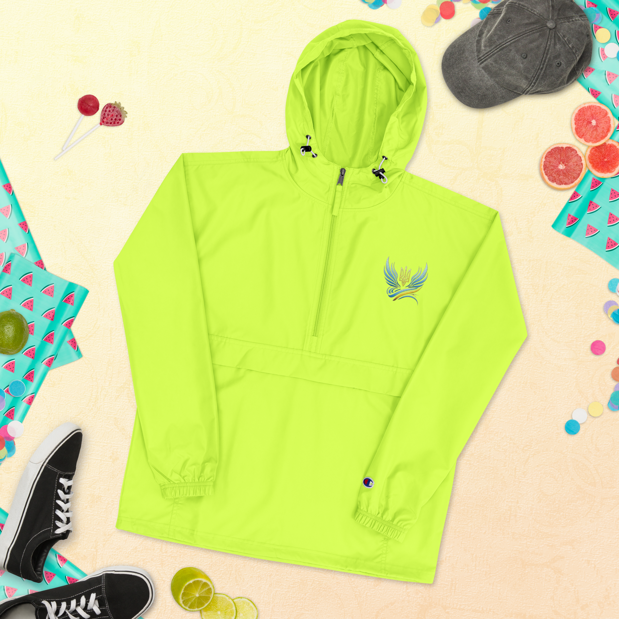Ukrainian Vibe Trizub embroidered Champion packable jacket, bright green with hood, displayed alongside casual accessories.
