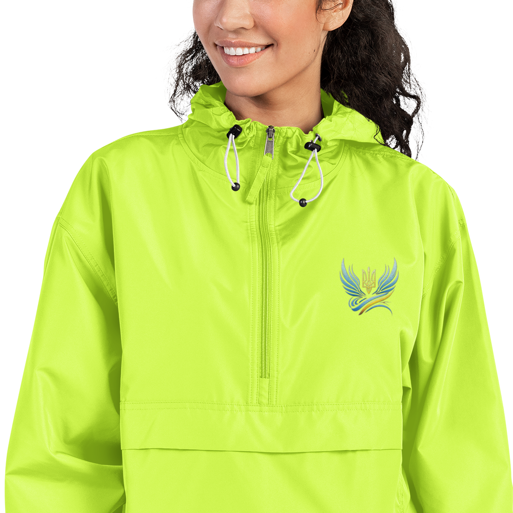 Woman wearing Ukrainian Vibe Trizub embroidered Champion packable jacket in lime green, featuring hood and kangaroo pocket.