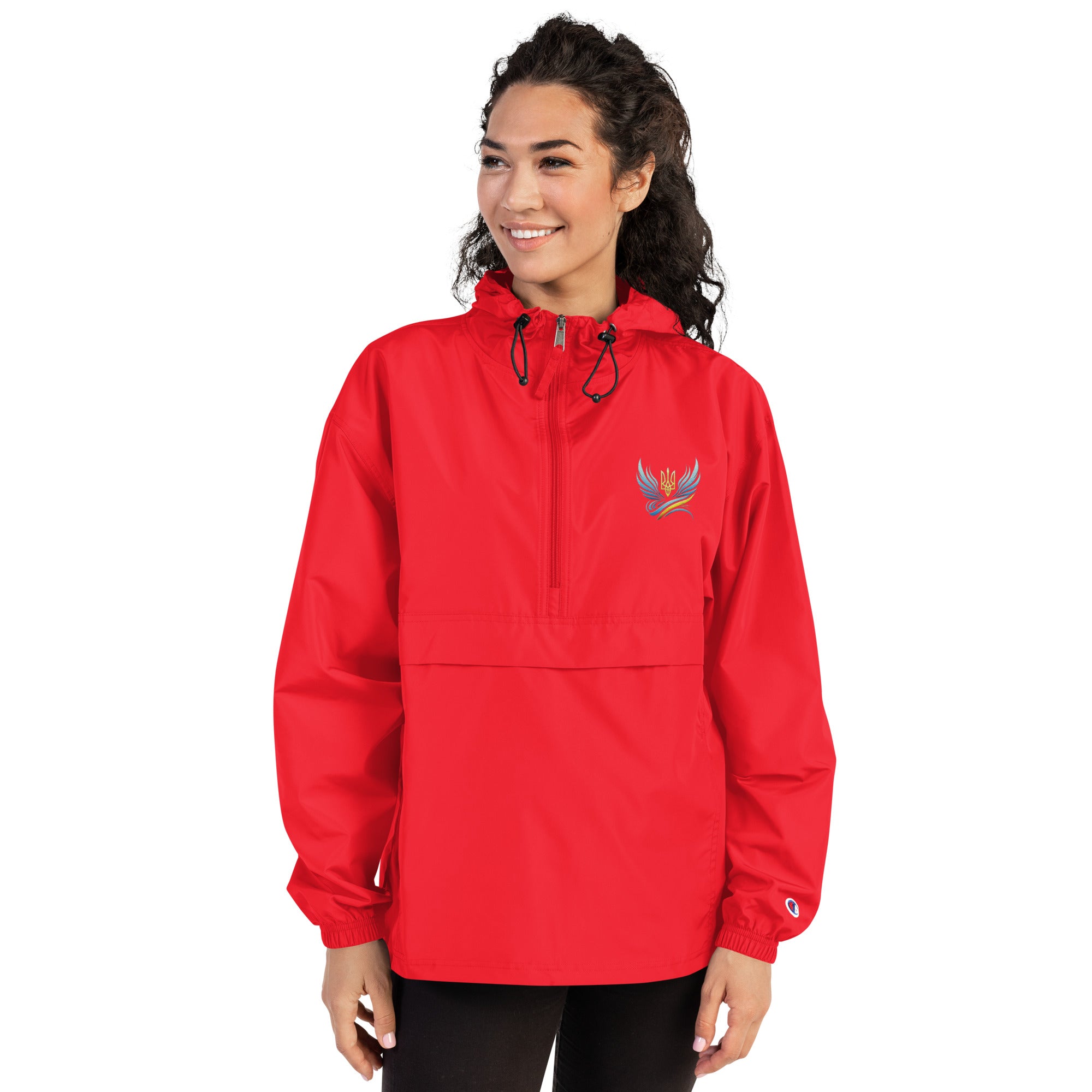 Woman wearing a red embroidered Champion packable jacket from the Ukrainian Vibe Trizub Collection with hood and kangaroo pocket.