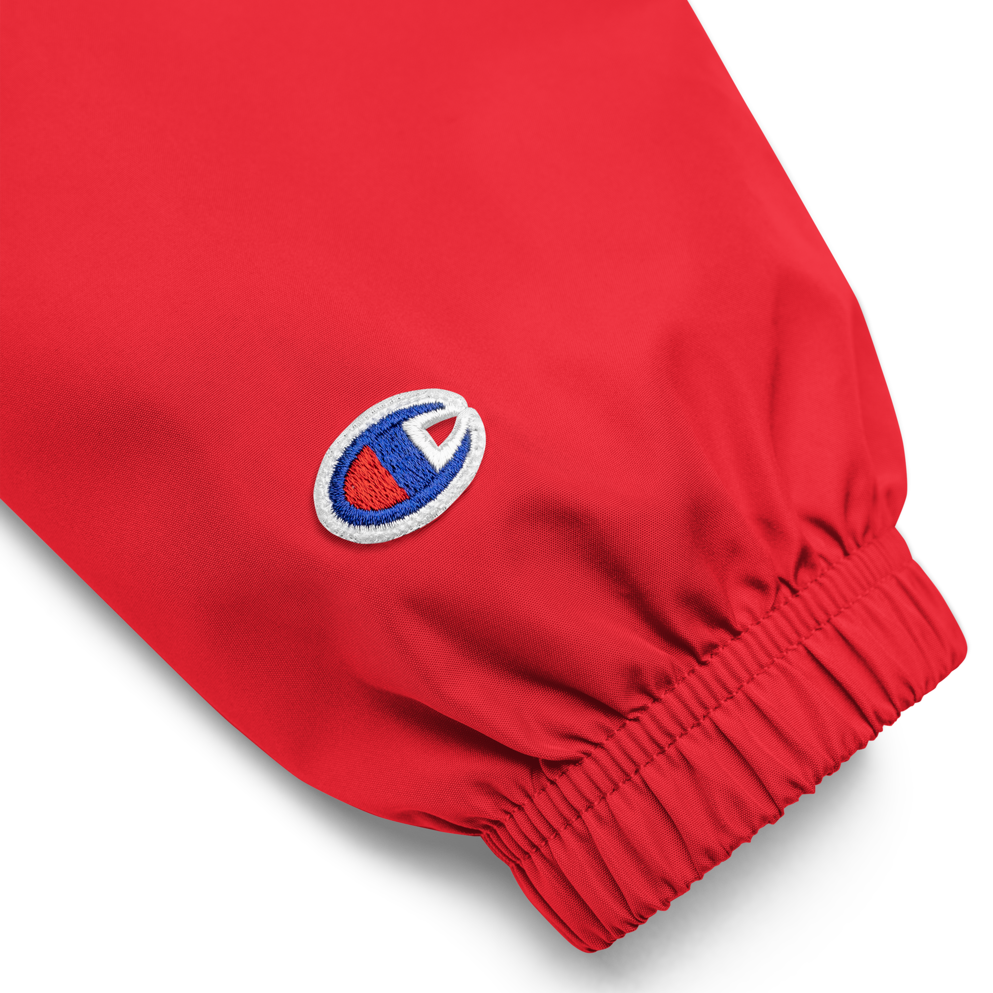 Close-up of embroidered logo on sleeve of red Champion packable jacket from the Ukrainian Vibe Trizub Collection.