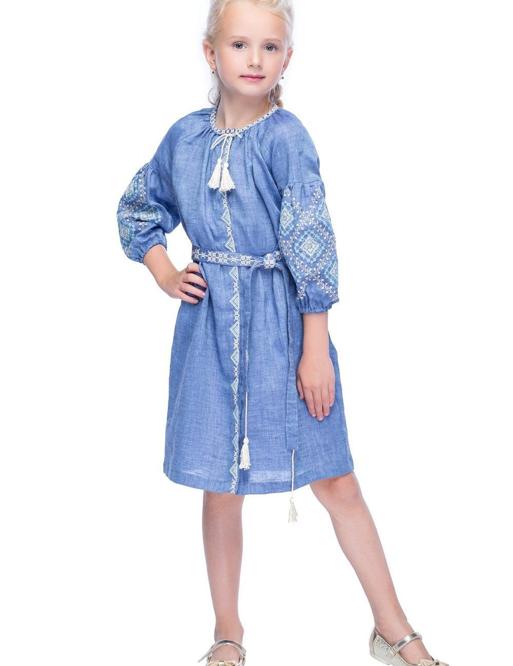 Girl wearing blue embroidered linen dress with woven belt and tassels, showcasing a traditional Ukrainian folk design.