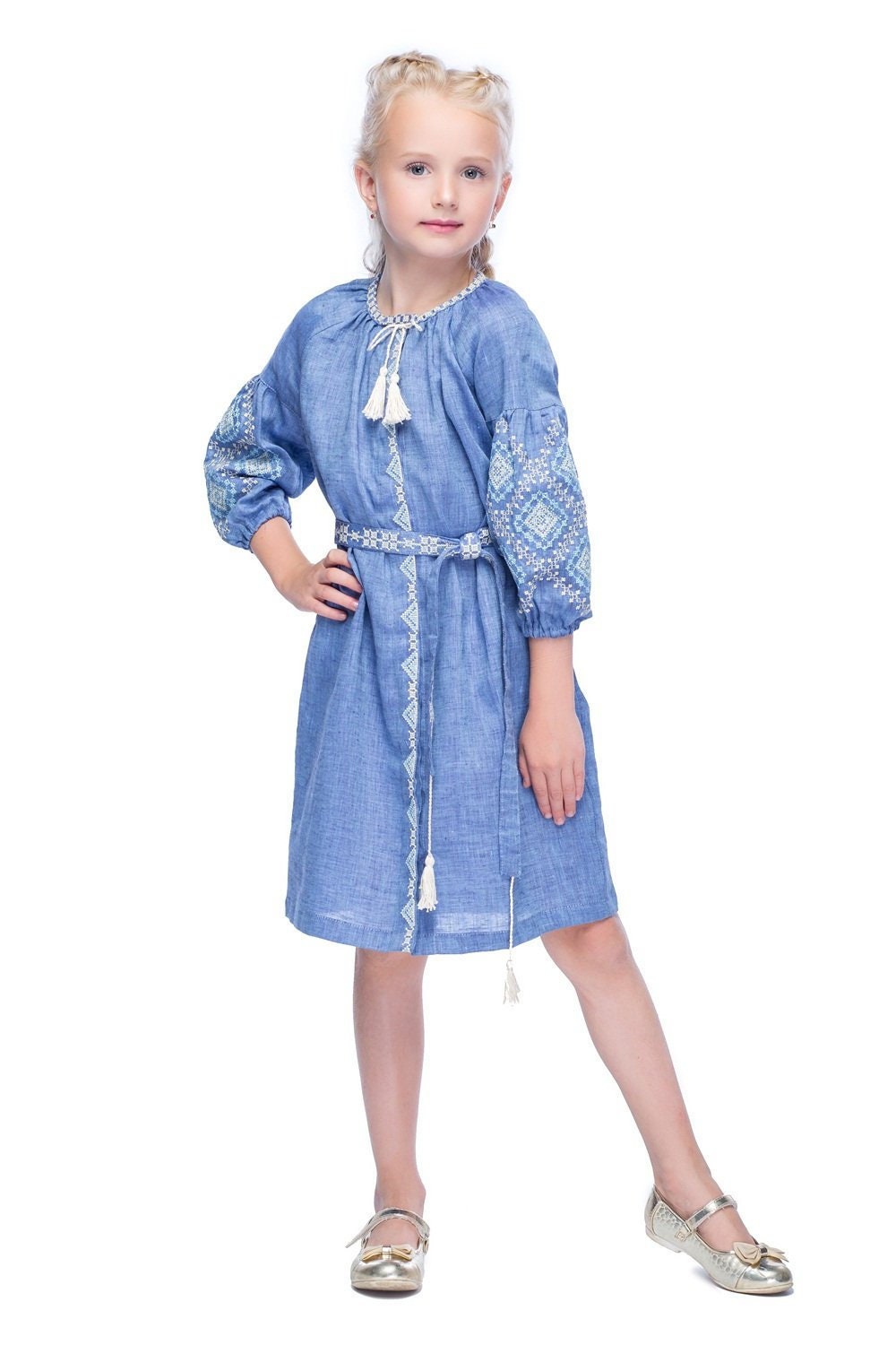 Girl wearing blue embroidered linen dress with woven belt and tassels, showcasing a traditional Ukrainian folk design.