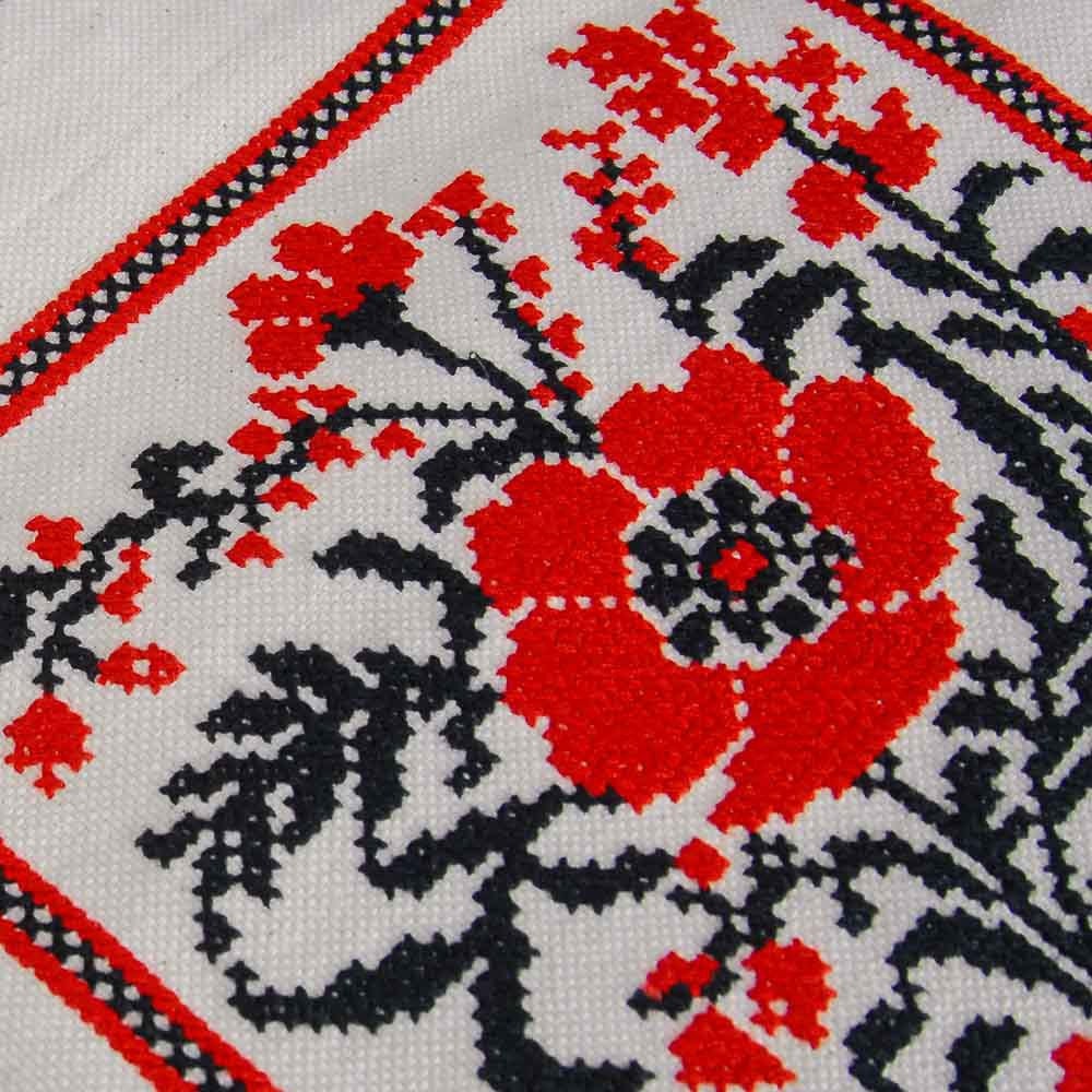 Close-up of floral embroidery on linen, showcasing vibrant red and black Ukrainian folk design, part of an eco-friendly tote bag.
