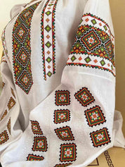 Close-up of embroidered linen Vyshyvanka blouse with traditional Ukrainian cross-stitch patterns in vibrant colors.