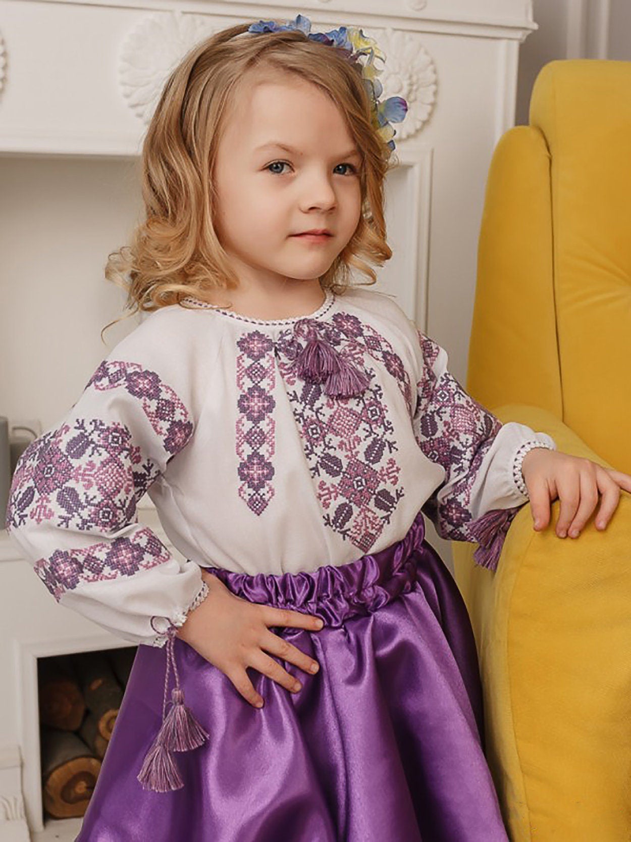 Girl wearing an embroidered Ukrainian blouse with purple cross-stitch patterns, traditional Vyshyvanka sorochka for festive occasions.