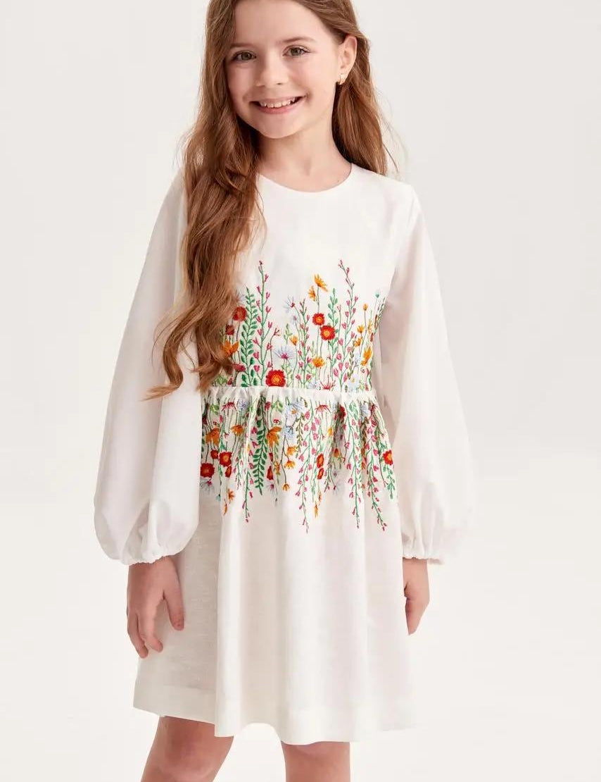 Girl wearing an embroidered linen dress with Ukrainian floral design, perfect for birthdays and special occasions.