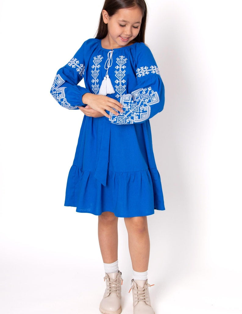 Girl wearing blue embroidered Vyshyvanka dress with traditional Ukrainian patterns.