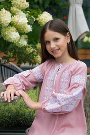 Girl wearing embroidered Vyshyvanka dress with traditional Ukrainian patterns, showcasing folk motifs in a garden setting.