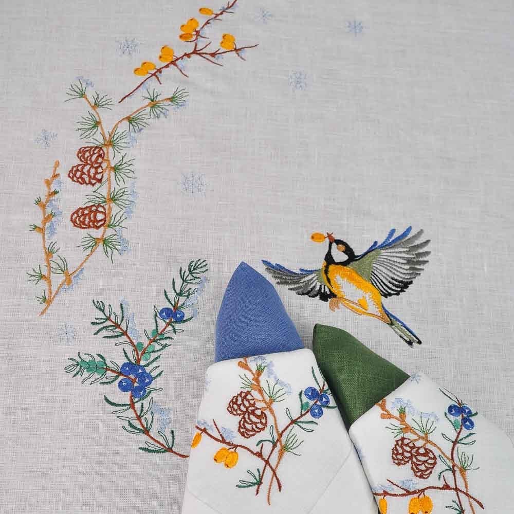 Embroidered linen tablecloth 'First Snow' featuring winter motifs, ideal for festive dining, seating 8-12 guests.