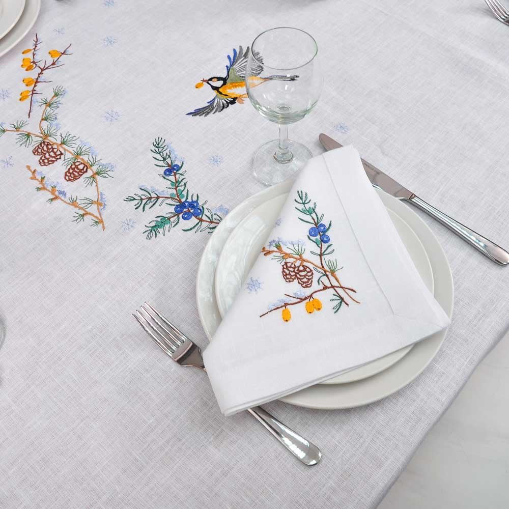 Embroidered linen tablecloth 'First Snow' with bird and pine motif, set for an elegant dinner, ideal for 8 to 12 guests.
