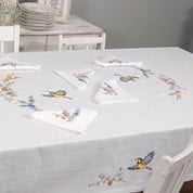 Embroidered linen tablecloth 'First Snow' on dining table, featuring Ukrainian motifs, ideal for festive gatherings.