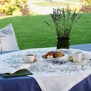 Embroidered linen tablecloth in 'Lavender' design on outdoor table with coffee set, showcasing Ukrainian folk artistry, 88x88 cm.