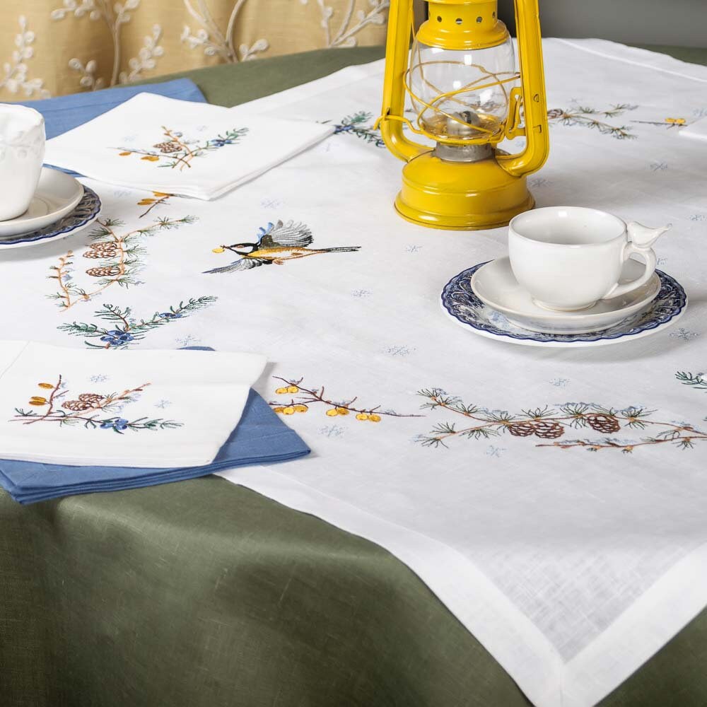 Embroidered linen tablecloth set with Ukrainian peony design, showcasing napkins and a vintage lamp on a dining table.
