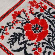 Close-up of floral embroidery on linen tote bag, featuring vibrant red and black folk patterns, perfect for summer beach outings.