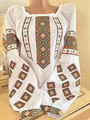 Embroidered linen Vyshyvanka blouse with Ukrainian cross-stitch patterns on white fabric, showcasing traditional craftsmanship.