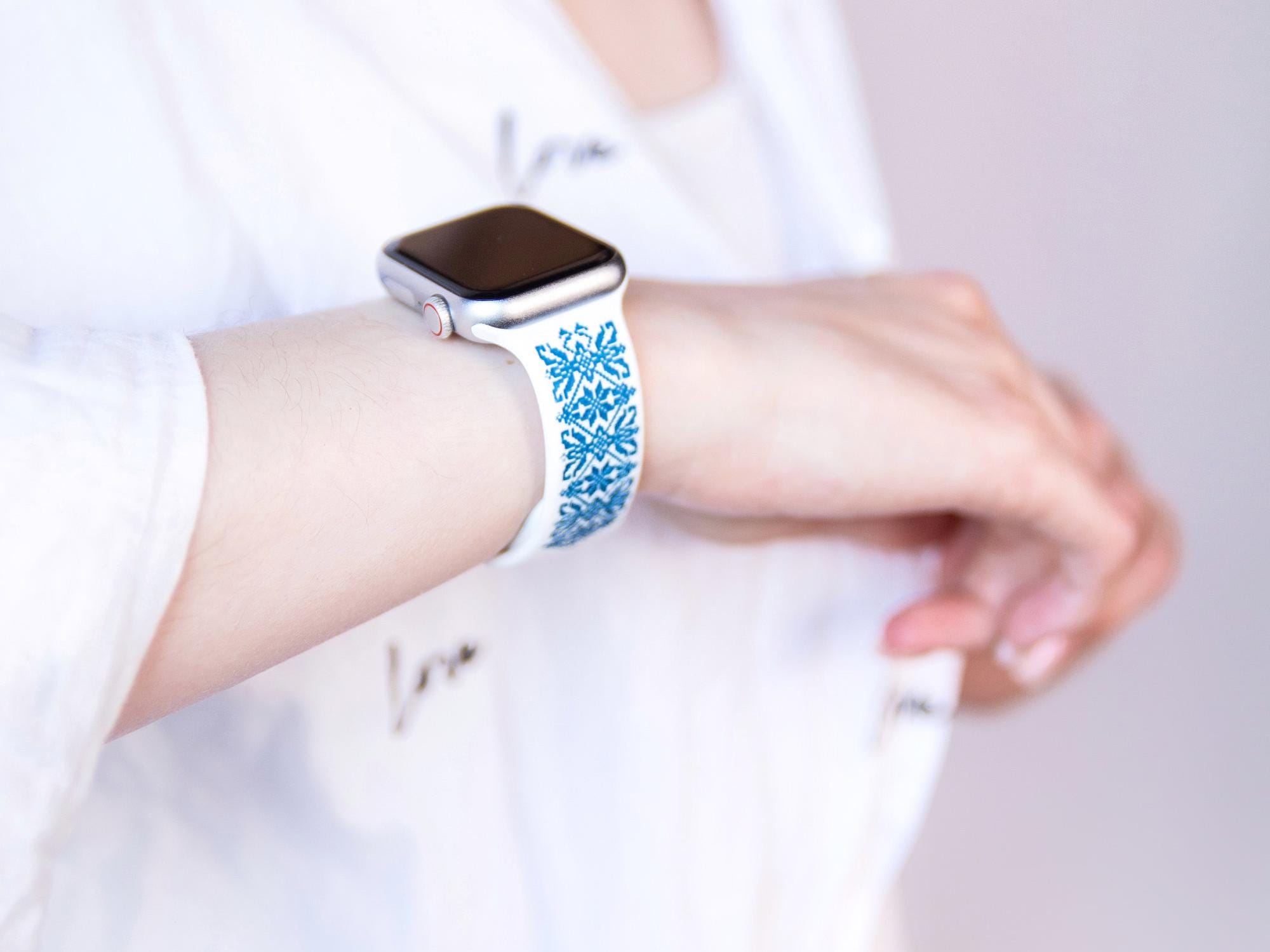 White and blue engraved Ukrainian embroidery Apple Watch band on wrist, showcasing intricate design and cultural heritage.