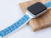 White and blue Ukrainian embroidery Apple Watch band, silicone strap, on wooden background, showcasing intricate design.