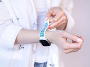Engraved Ukrainian embroidery Apple Watch band in white and blue silicone, a handcrafted waterproof accessory being worn.