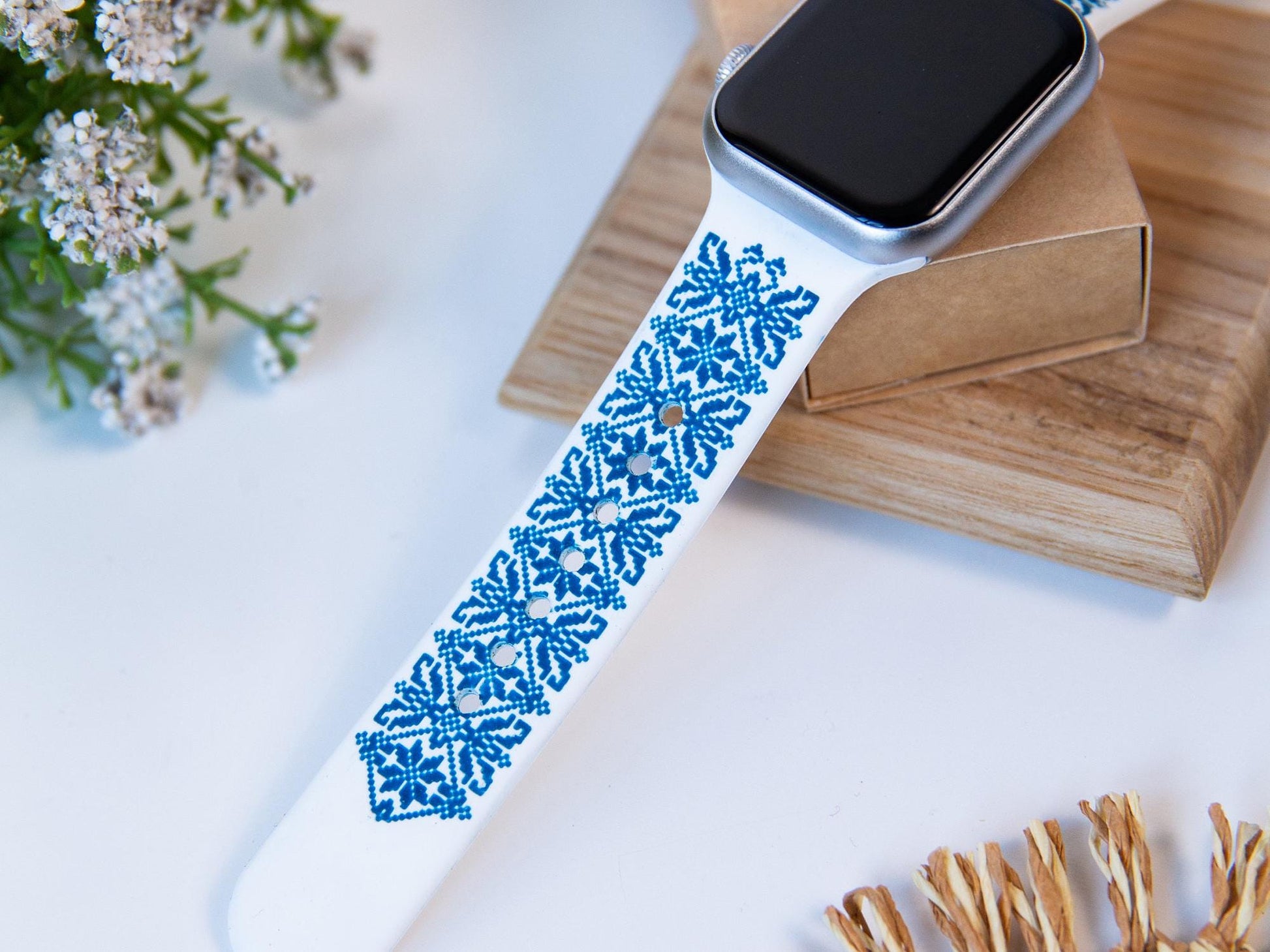 White and blue Apple Watch band with engraved Ukrainian embroidery design, showcasing cultural craftsmanship.