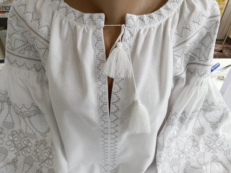 Women's ethnic white vyshyvanka blouse with traditional Ukrainian cross-stitch embroidery on homespun fabric.