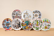 Decorative souvenir plates with city landmarks, featuring vibrant illustrations from major European cities, displayed with wooden stands.
