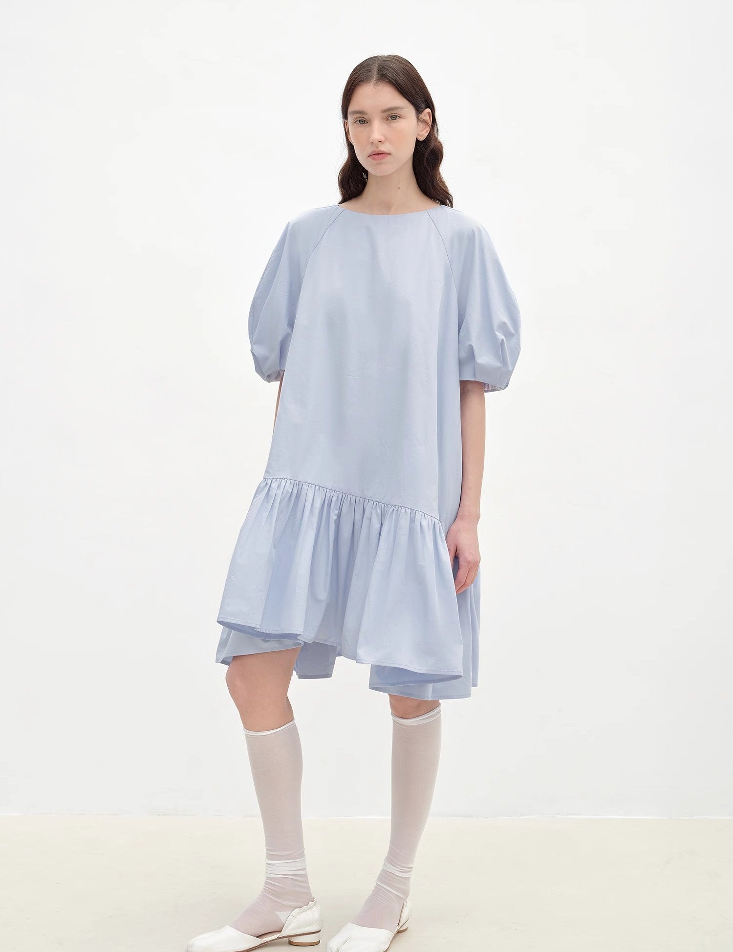 Woman wearing Evaira Puff-Sleeve Cotton Dress with round neckline and asymmetric hem showcasing a romantic summer style.
