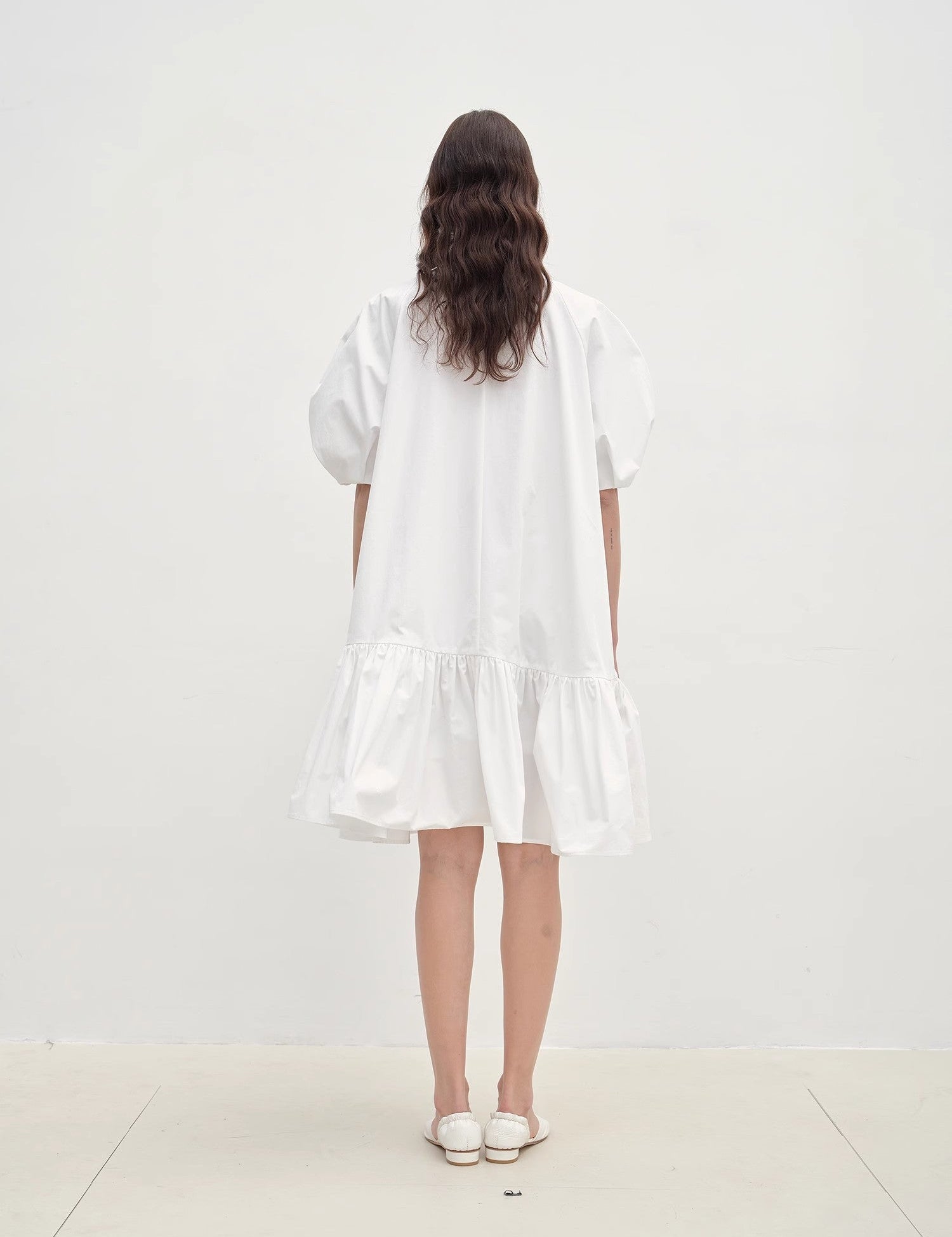 Back view of Evaira Puff-Sleeve Cotton Dress in white, showcasing sculpted puff sleeves and asymmetric hem.