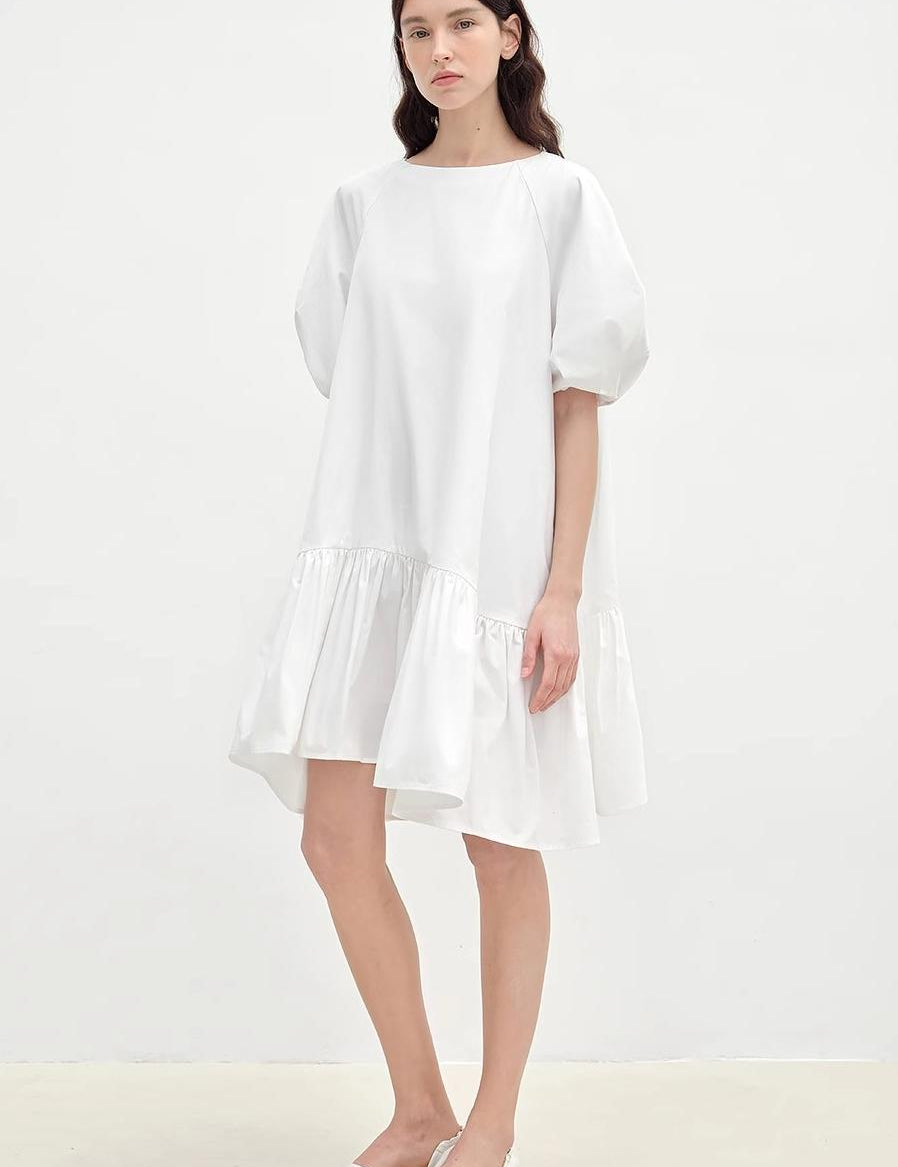 Evaira white puff-sleeve cotton dress with round neckline and asymmetric hem, showcasing vintage-inspired summer elegance.