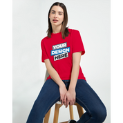Woman wearing a red print-on-demand t-shirt with text 'Your Design Here', sitting on a stool, showcasing custom apparel options.