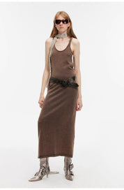 Model wearing Feryn enzyme-washed vest dress with U-neckline and curved back, styled with a belt and scarf, showcasing a chic look.