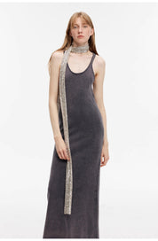 Woman wearing Feryn Enzyme-Washed Vest Dress in dark cotton with U-neckline, accessorized with a sparkling scarf, showcasing casual elegance.